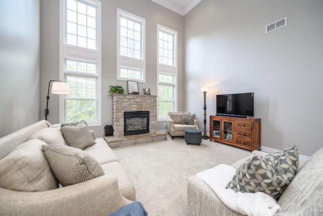 living area featuring visible vents, a healthy amount of sunlight, ornamental molding, and a high ceiling