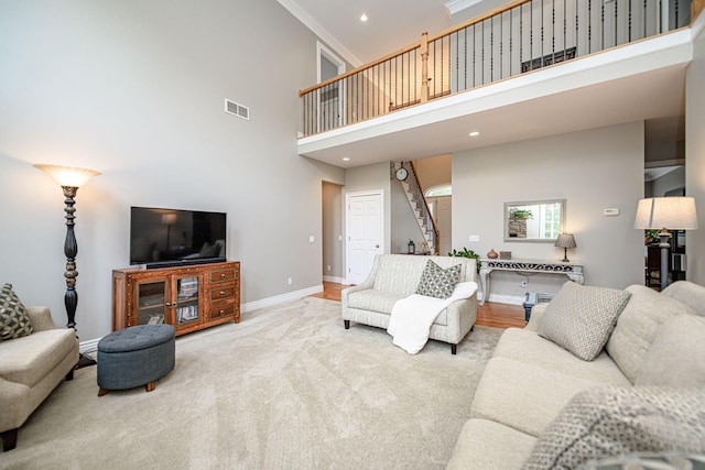 carpeted living area featuring recessed lighting, stairway, baseboards, visible vents, and a towering ceiling