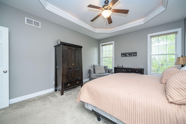 bedroom featuring a tray ceiling, a ceiling fan, visible vents, baseboards, and light colored carpet