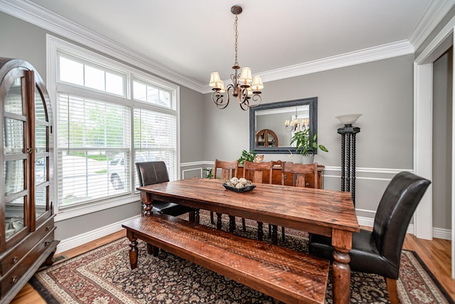 dining room with a chandelier, crown molding, light wood finished floors, and baseboards