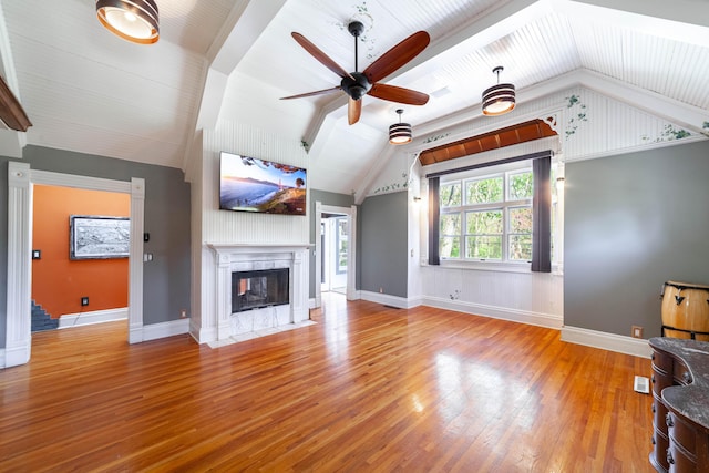 unfurnished living room with vaulted ceiling, a ceiling fan, a multi sided fireplace, wood-type flooring, and baseboards