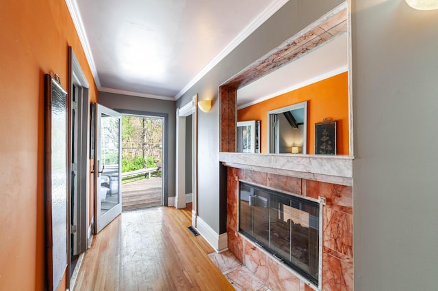 unfurnished living room with a multi sided fireplace, ornamental molding, baseboards, and light wood-style flooring