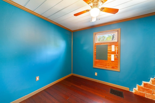 spare room with dark wood-style floors, baseboards, visible vents, ceiling fan, and ornamental molding