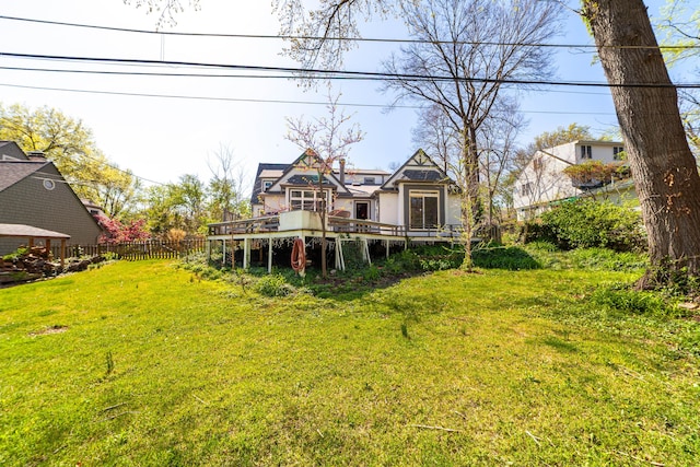 rear view of house featuring a lawn, fence, and a deck