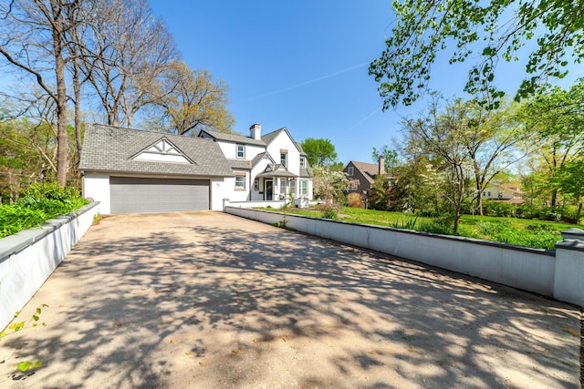 view of front of home featuring an attached garage, a chimney, concrete driveway, and fence