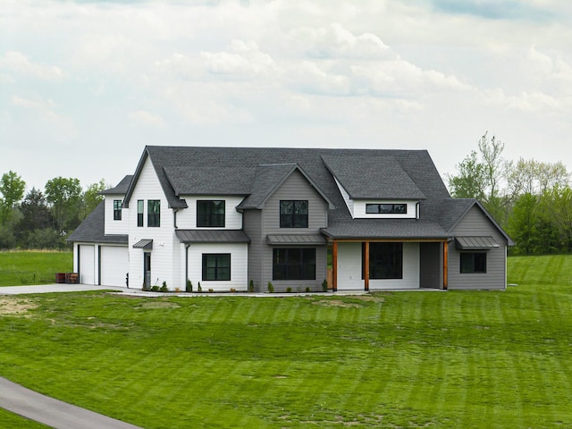 modern farmhouse with concrete driveway, a standing seam roof, metal roof, a shingled roof, and a front yard