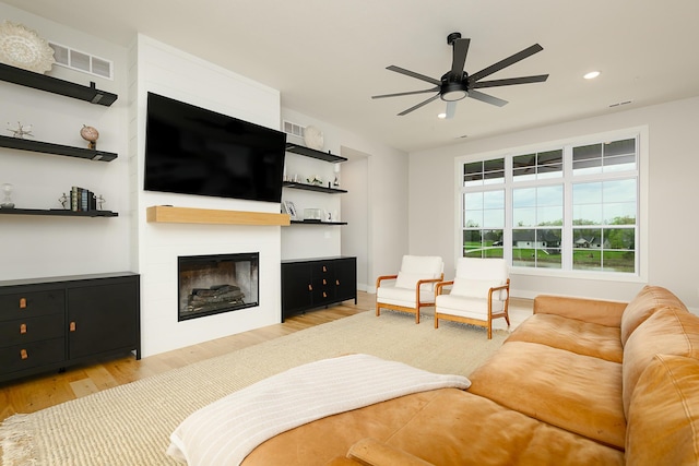 living room featuring recessed lighting, ceiling fan, light wood finished floors, a fireplace, and visible vents