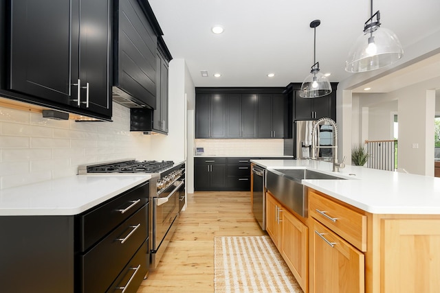 kitchen featuring tasteful backsplash, a sink, stainless steel appliances, light countertops, and dark cabinetry