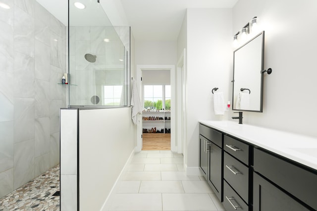 bathroom featuring a sink, a walk in shower, tile patterned floors, double vanity, and baseboards