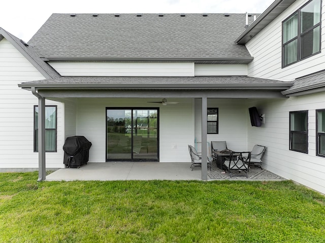 back of property with a patio, a ceiling fan, a lawn, and a shingled roof