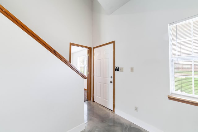 entrance foyer with stairway, finished concrete flooring, and baseboards