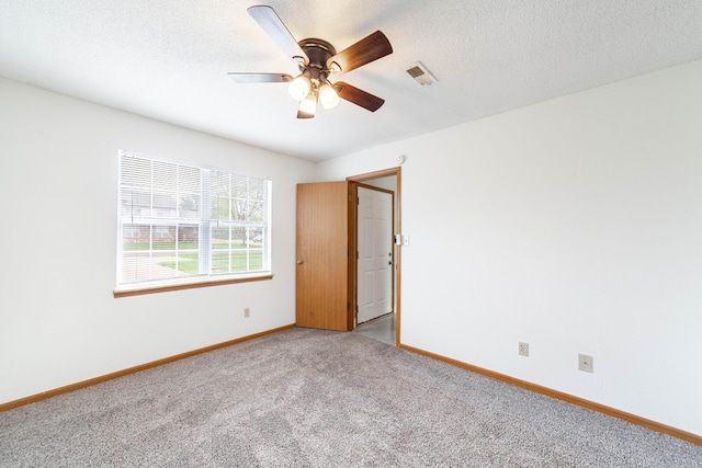 unfurnished room with visible vents, light carpet, baseboards, a textured ceiling, and ceiling fan