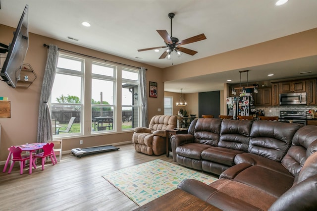 living area with baseboards, light wood-type flooring, ceiling fan with notable chandelier, and recessed lighting