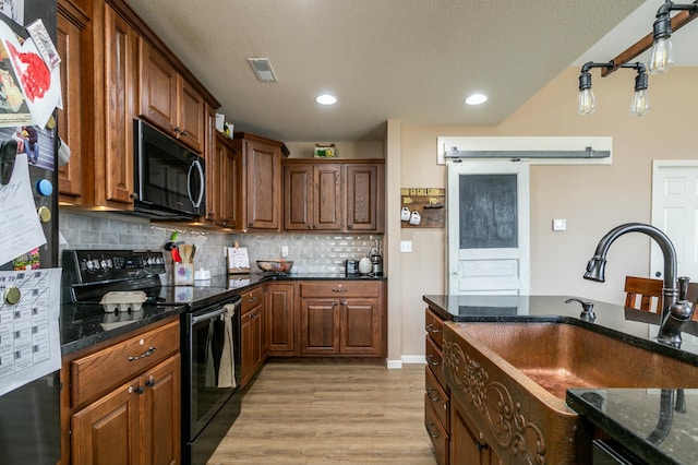 kitchen with decorative backsplash, a sink, light wood-style floors, freestanding refrigerator, and electric range