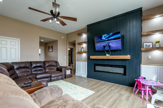 living area with ceiling fan, wood finished floors, and a fireplace