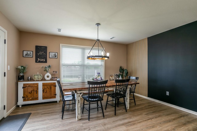 dining room featuring a notable chandelier, baseboards, wood finished floors, and visible vents