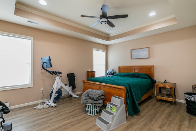 bedroom with a raised ceiling, visible vents, and ornamental molding