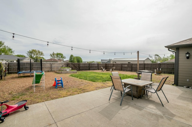 view of patio featuring outdoor dining area, a trampoline, and a fenced backyard