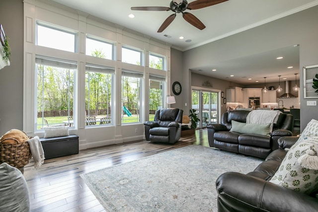 living room featuring ceiling fan, recessed lighting, ornamental molding, and wood-type flooring