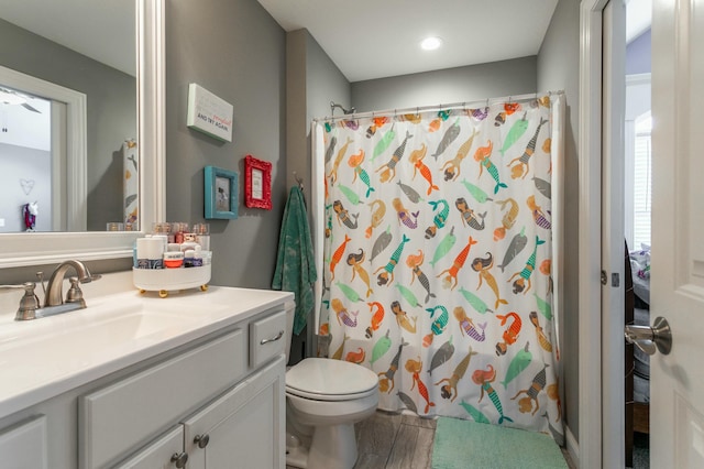 full bath with curtained shower, wood finished floors, toilet, and vanity