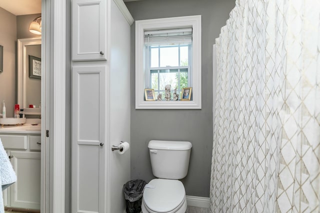 full bath featuring toilet, vanity, and baseboards
