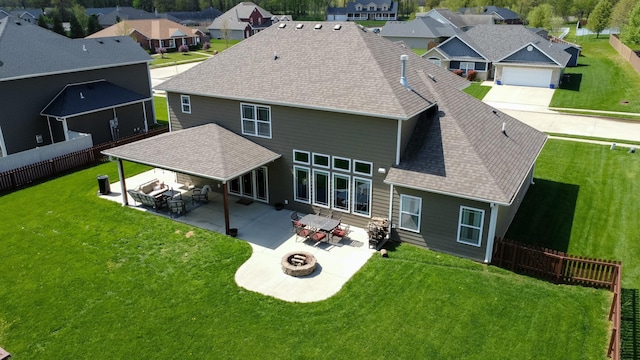 back of property with a residential view, a shingled roof, a fire pit, and a fenced backyard
