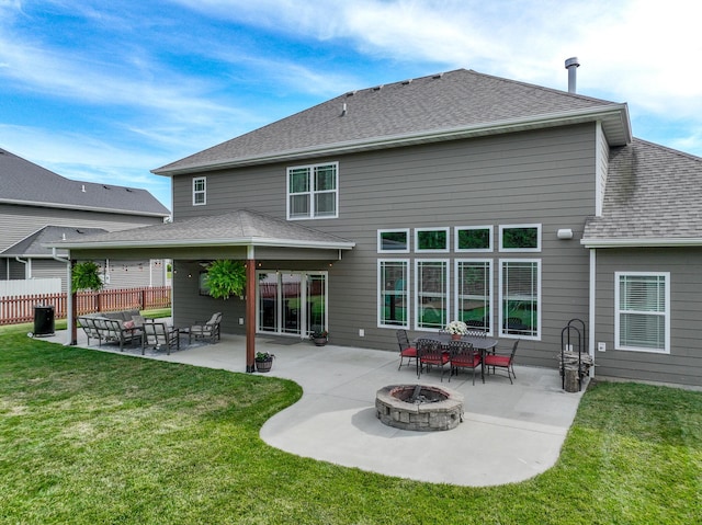 rear view of house featuring fence, a lawn, an outdoor living space with a fire pit, a patio area, and roof with shingles