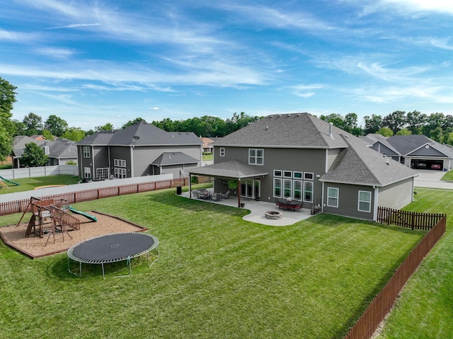 back of property featuring a residential view, a trampoline, a patio area, an outdoor fire pit, and a yard