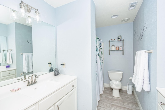 bathroom with toilet, baseboards, visible vents, and vanity