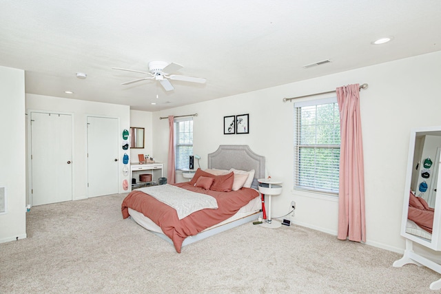 carpeted bedroom with visible vents, a ceiling fan, baseboards, and multiple windows