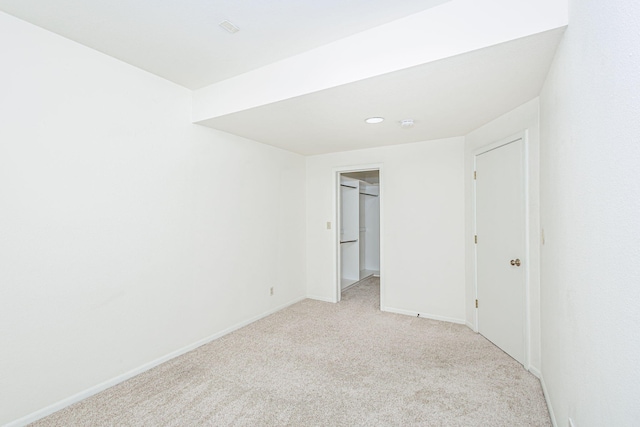 unfurnished bedroom with light colored carpet, recessed lighting, baseboards, and a walk in closet