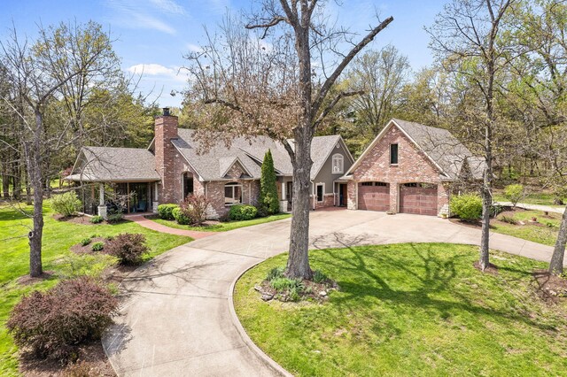 view of front of home featuring roof with shingles, a front lawn, driveway, a chimney, and brick siding