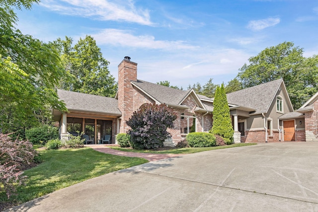 7114 W River Oaks Rd, Columbia, MO 65203 - view of front of property with a front yard, a shingled roof, brick siding, a chimney, and driveway
