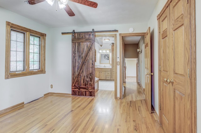 302 Park Rd, Fayette, MO 65248 - unfurnished room featuring ceiling fan, baseboards, a barn door, and light wood-style floors