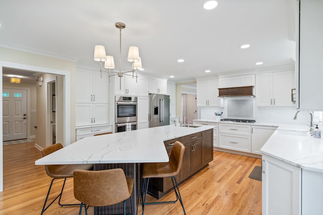 kitchen with a sink, backsplash, stainless steel appliances, and white cabinetry