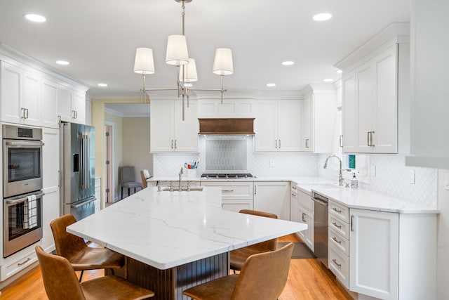 kitchen with a kitchen breakfast bar, a sink, white cabinetry, and stainless steel appliances