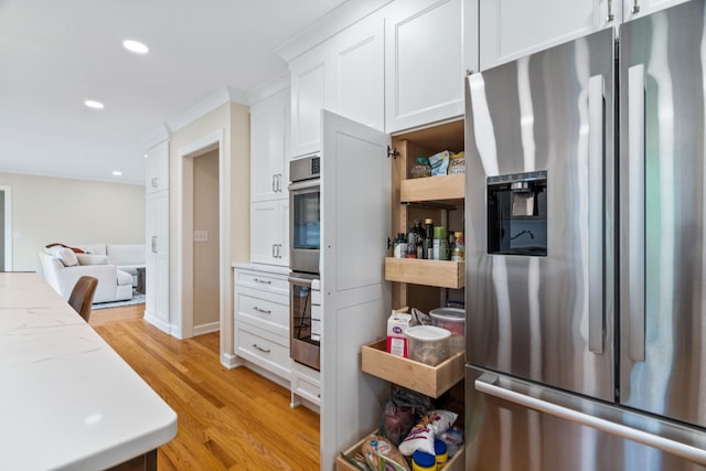 kitchen with light stone counters, light wood-style flooring, white cabinets, stainless steel appliances, and recessed lighting