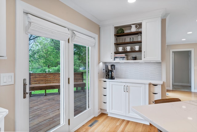 interior space featuring tasteful backsplash, open shelves, white cabinets, visible vents, and light wood-type flooring