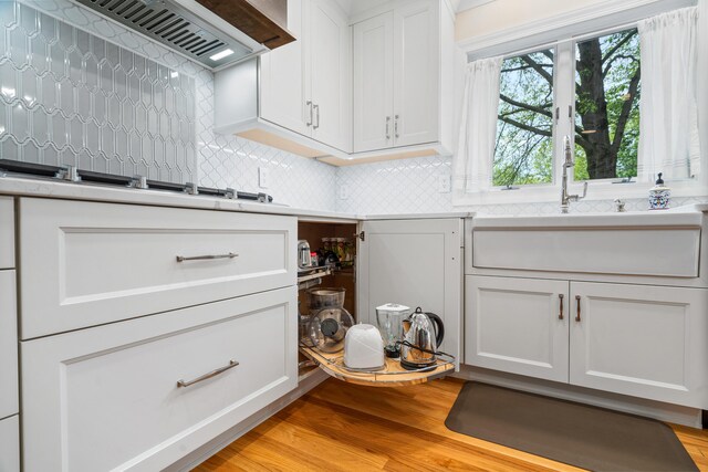 interior space featuring premium range hood, backsplash, white cabinetry, and light countertops