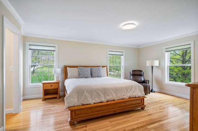bedroom with ornamental molding, light wood-style flooring, and baseboards
