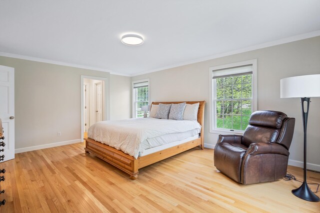 bedroom with ornamental molding, light wood-style flooring, and baseboards