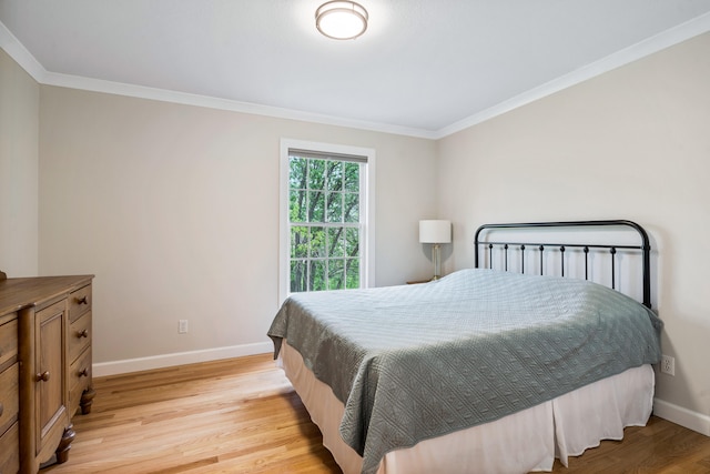 bedroom featuring crown molding, light wood-style flooring, and baseboards