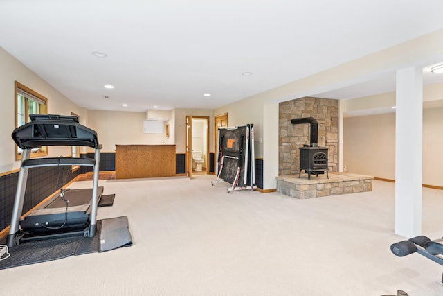 exercise room with a wood stove, recessed lighting, and carpet flooring