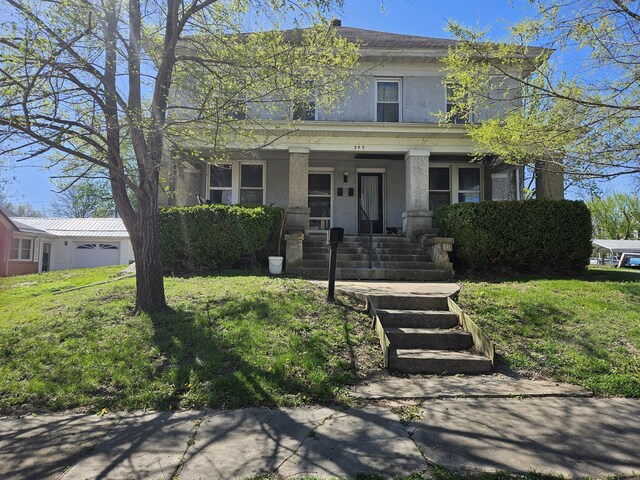 american foursquare style home with stucco siding and covered porch