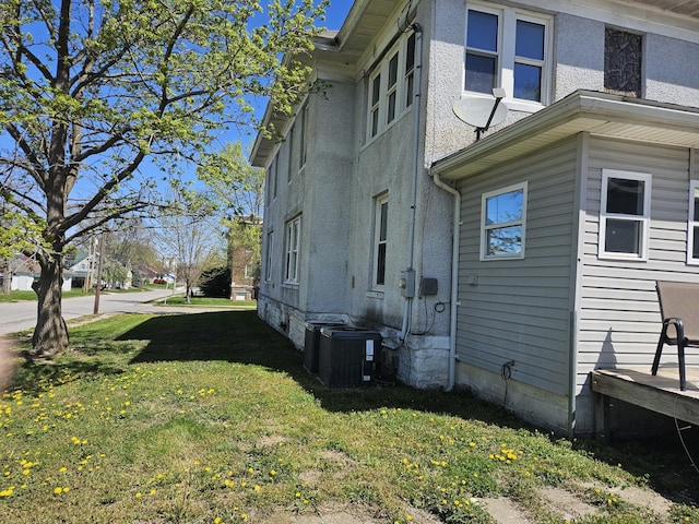 view of side of home featuring a lawn and cooling unit