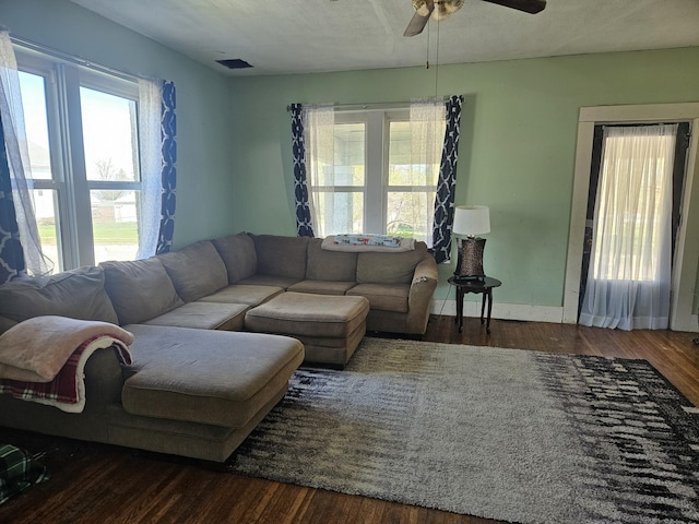 living room with baseboards, visible vents, wood finished floors, and ceiling fan