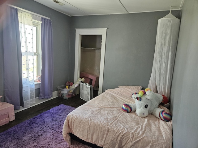 bedroom with visible vents, wood finished floors, and a closet