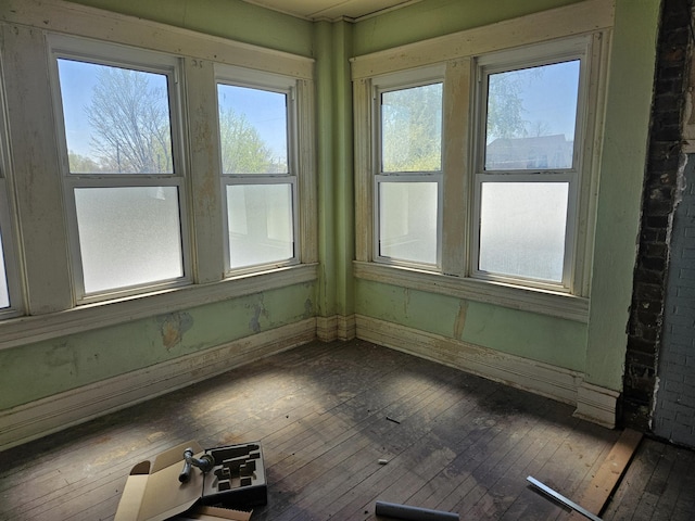 unfurnished sunroom with a healthy amount of sunlight and wood-type flooring
