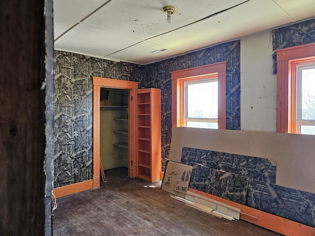 bedroom with wood finished floors, wallpapered walls, and multiple windows