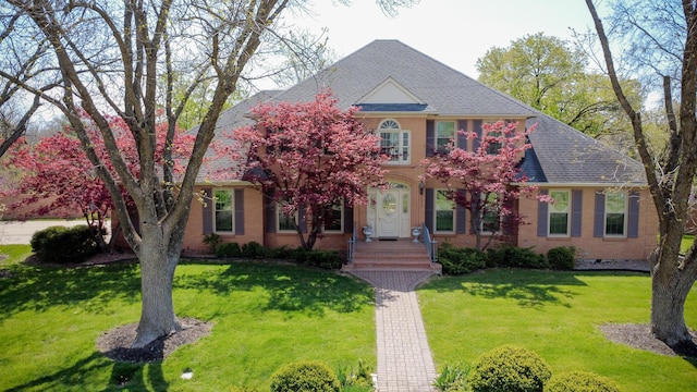 view of front facade featuring brick siding, roof with shingles, and a front yard